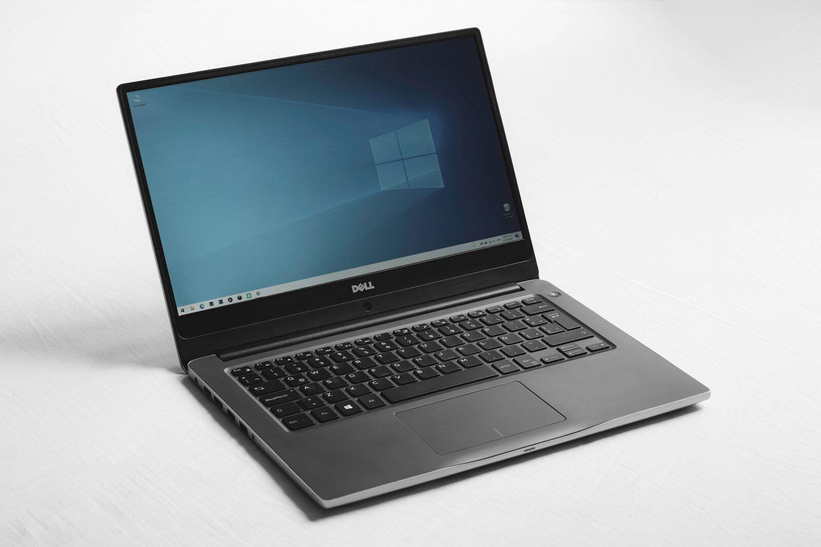 A Dell laptop with a blue desktop screen on a white surface